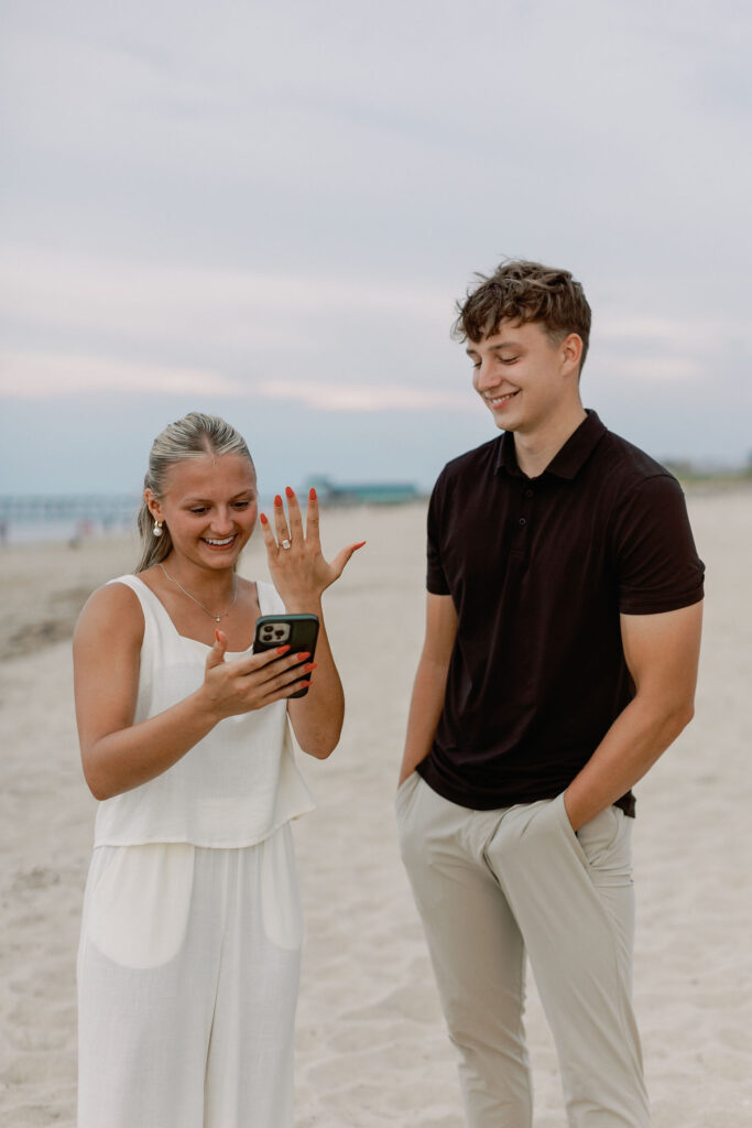 Newly engaged couple showing off an engagement ring after a surprise proposal on the Crystal Coast.