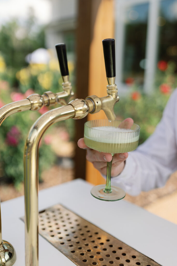 An interactive cocktail bar sits in the rose garden for guests during cocktail hour at this outdoor wedding.