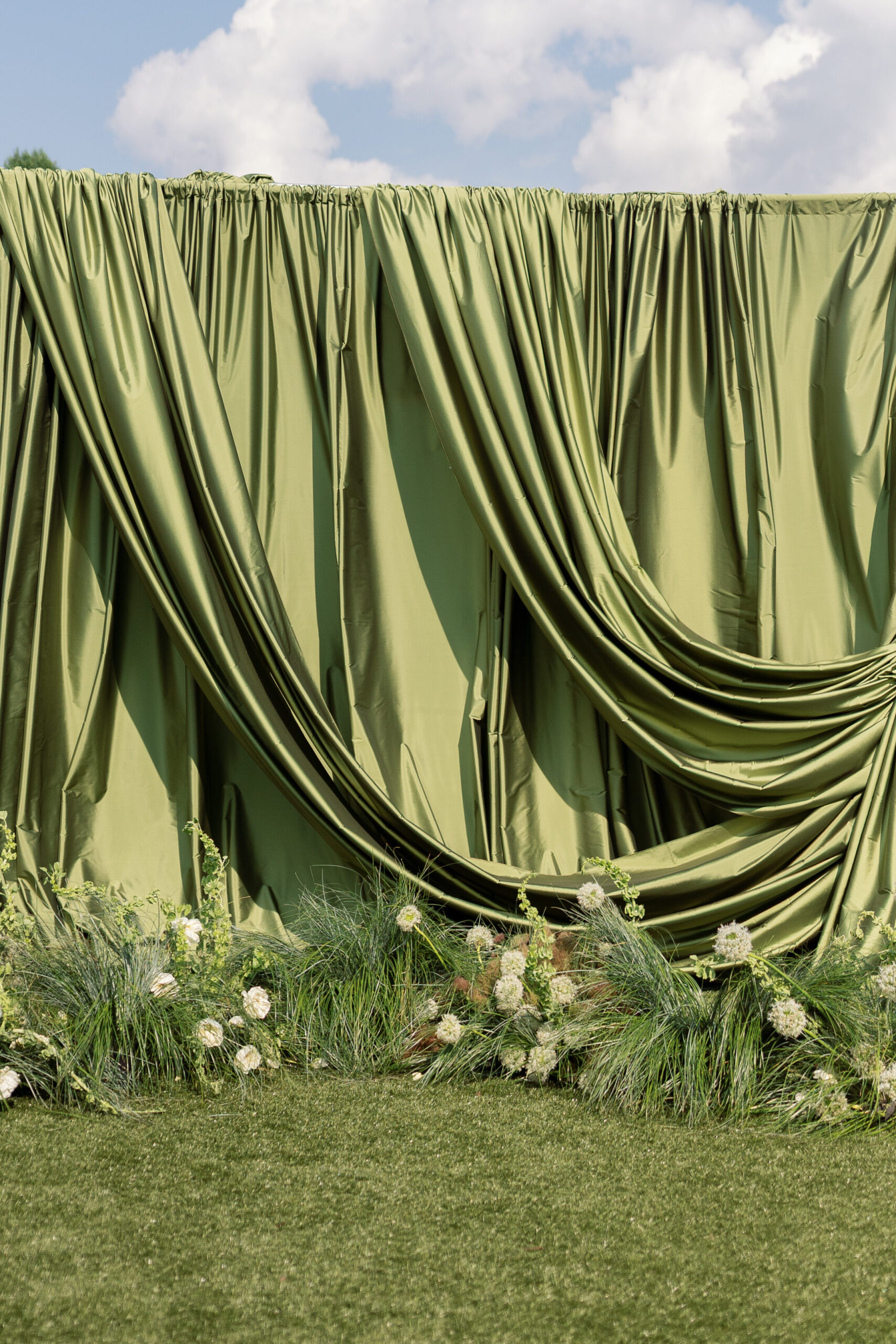 A sculptural draping stands in front of the altar at an outdoor wedding 