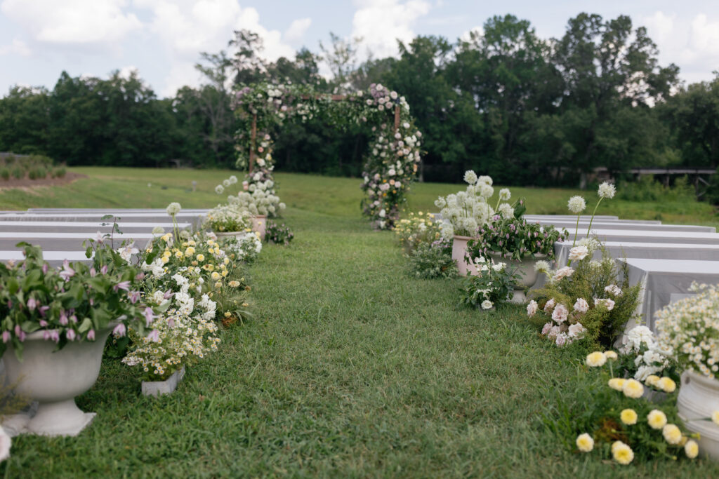 Outdoor garden wedding ceremony at Donovan Manor with floral-filled aisle and greenery arch