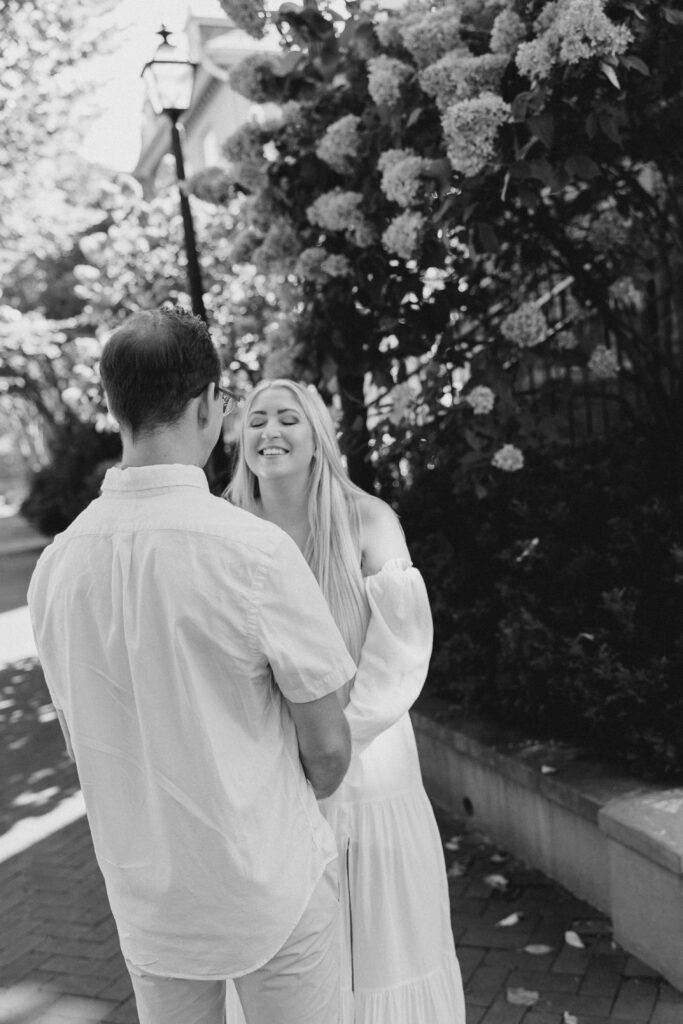 Black and white photo of couple smiling near blooming hydrangeas in Frederick Maryland