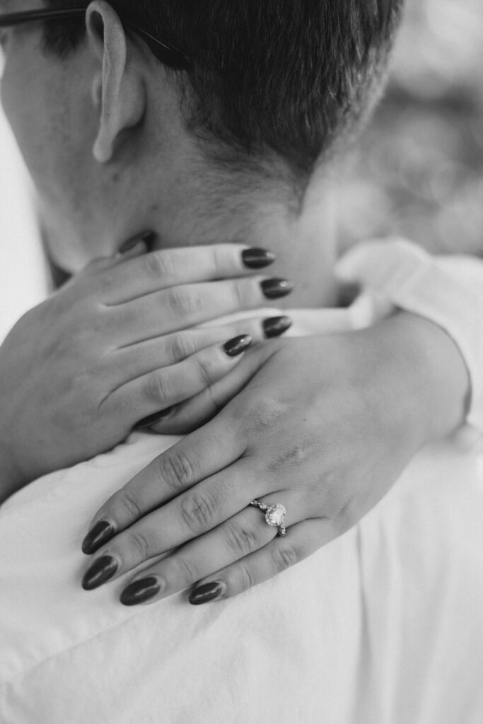 Bride resting hands on groom’s shoulders showing diamond engagement ring