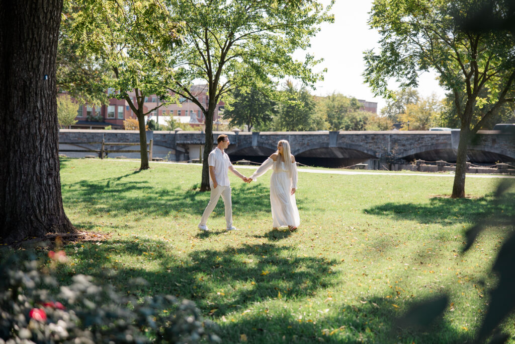 Couple walking hand in hand through Baker Park during golden hour in Downtown Frederick