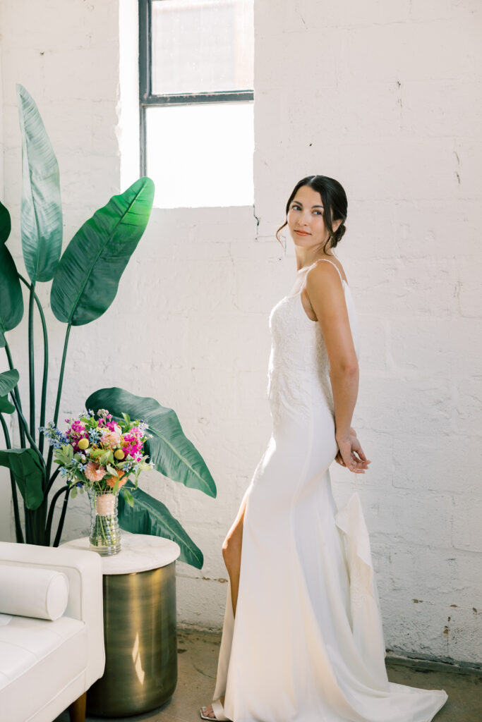A bride poses by a large palm plant during her tropical wedding in Florida