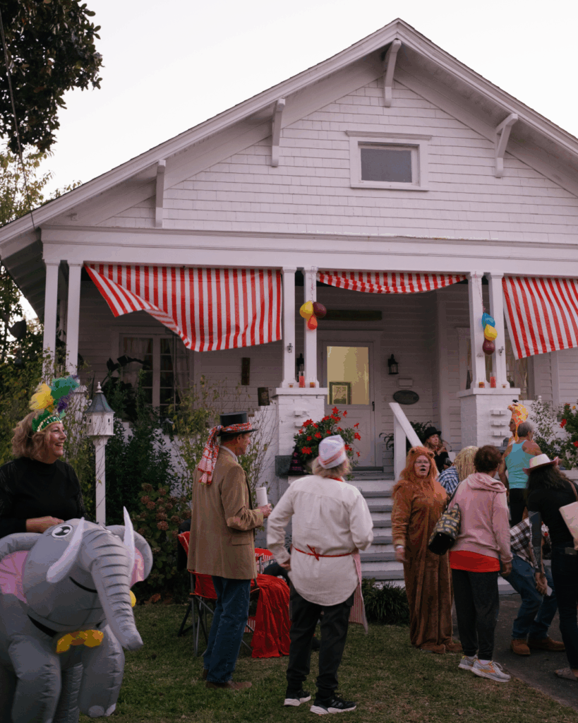 Beaufort NC Halloween neighborhood gathering with costumes and striped circus decorations on a white craftsman porch — captured by Beaufort NC photographer Hailey Rae Photography.