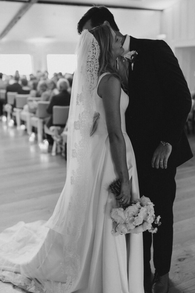 Bride and groom share a first kiss as they walk down the aisle at the Dunes Club