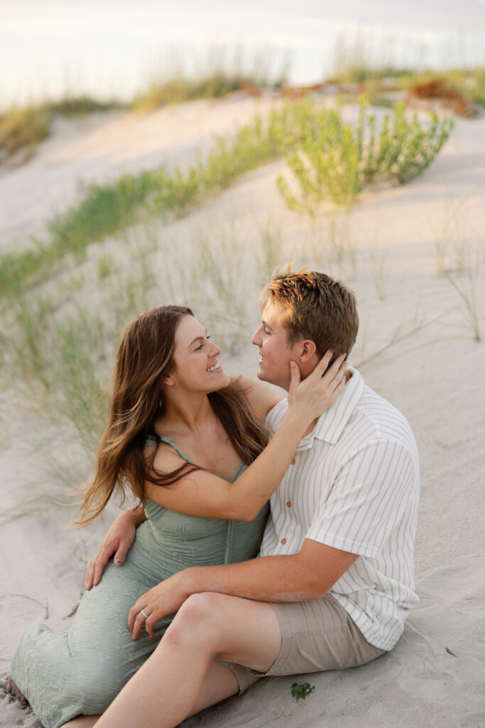 A couple embraces on the beach for their family photo session on the Crystal Coast. 