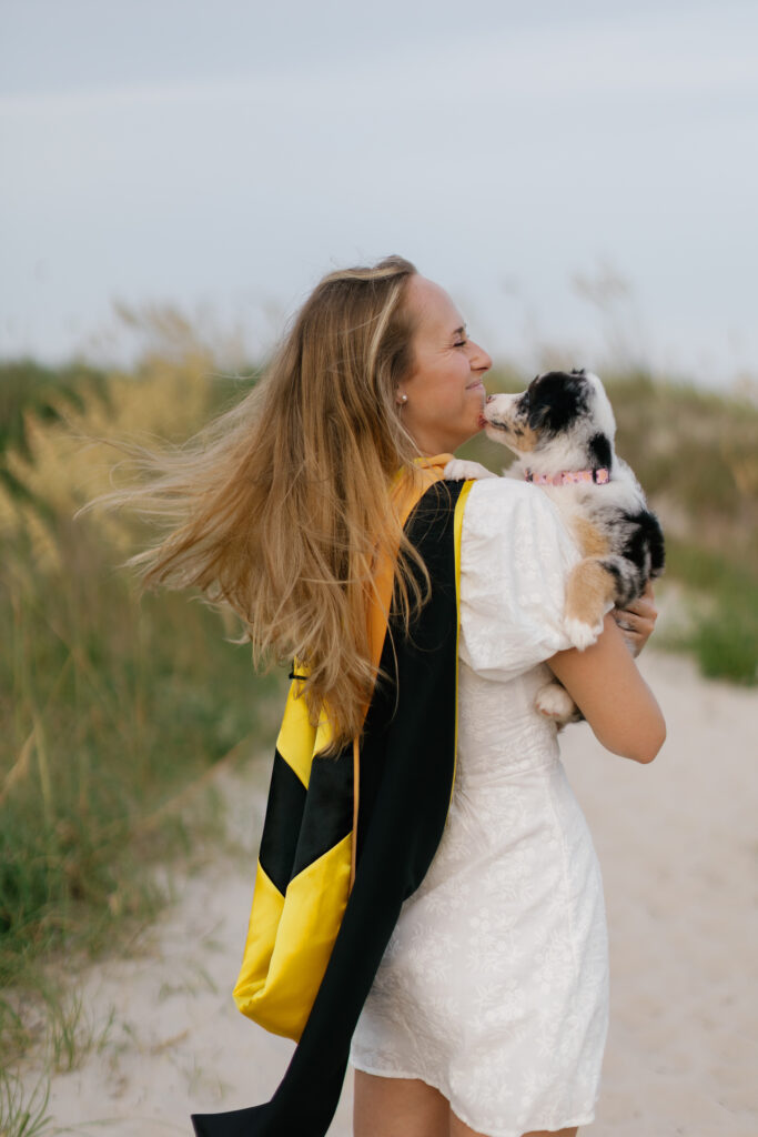 Candid graduation photo with puppy on the beach along the Crystal Coast of North Carolina