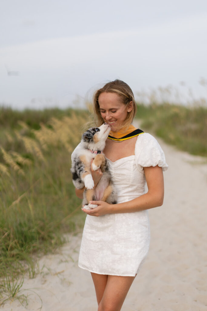 MSW graduate posing with her puppy during senior photos at Atlantic Beach, North Carolina