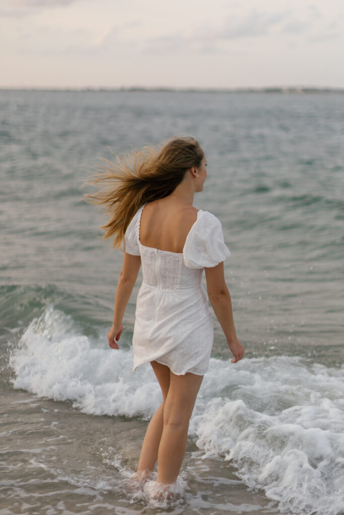 Graduate walking through the ocean during senior pictures at Atlantic Beach NC