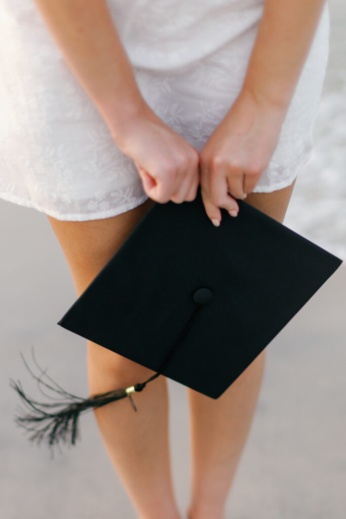 A graduate holds her graduation cap in her hand as she walks Fort Macon State Park