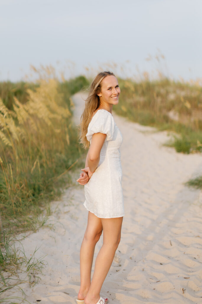 Graduate walking through coastal dunes during a Crystal Coast graduation session